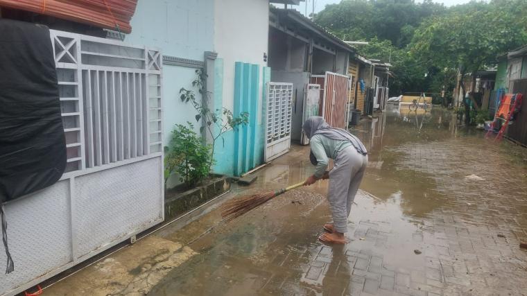 Salah satu warga saat membersihkan sisa-sisa banjir di gank merdeka B2, Perumahan Grand Sutera Kota Serang.