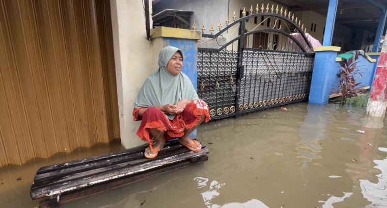 Salah satu warga terdampak banjir, menunggu air surut didepan rumahnya.